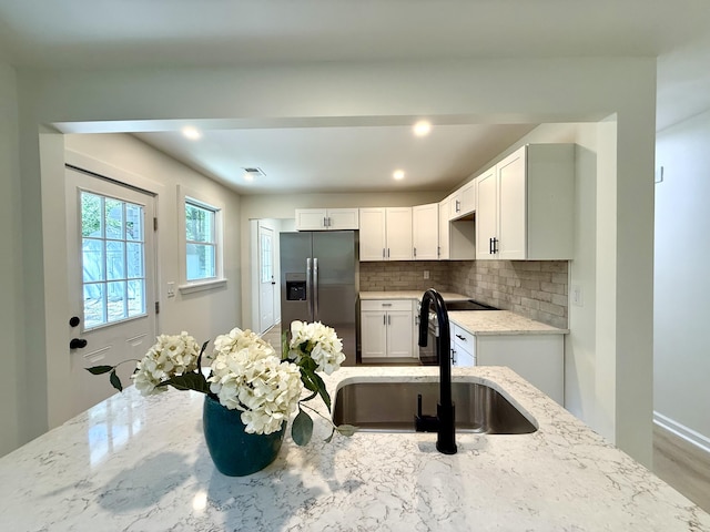 6086 Chisolm Rd, Johns Island, SC 29455 - kitchen featuring decorative backsplash, stainless steel refrigerator with ice dispenser, white cabinets, light stone counters, and a sink