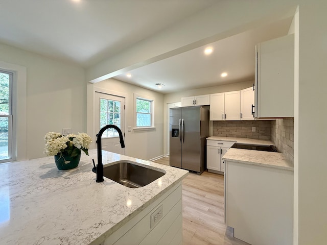 6086 Chisolm Rd, Johns Island, SC 29455 - kitchen featuring backsplash, light stone countertops, a sink, white cabinets, and stainless steel fridge