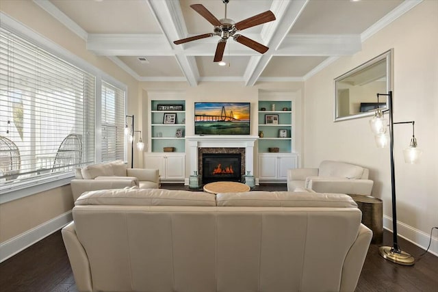 living area with baseboards, beamed ceiling, dark wood-style floors, a glass covered fireplace, and coffered ceiling