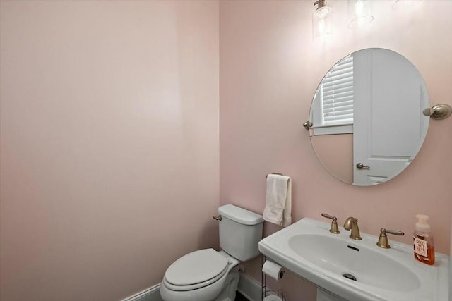 bathroom with toilet, baseboards, and a sink