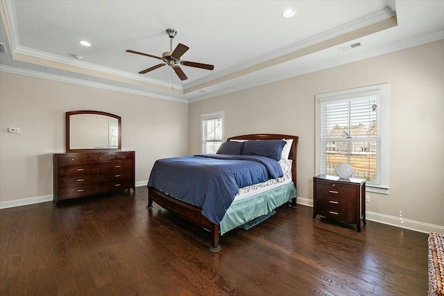 bedroom with baseboards, crown molding, a tray ceiling, and wood finished floors