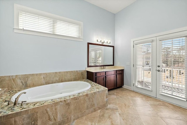 bathroom featuring vanity, a bath, and french doors