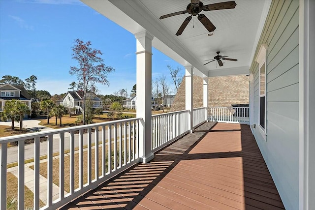 wooden deck featuring a residential view, covered porch, and ceiling fan