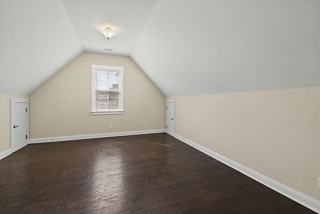 additional living space with visible vents, baseboards, wood finished floors, and vaulted ceiling