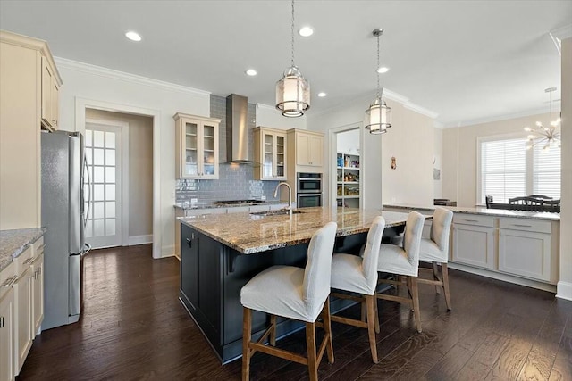 kitchen with a kitchen bar, backsplash, dark wood-style floors, stainless steel appliances, and wall chimney range hood