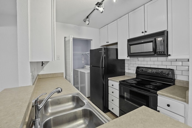 kitchen featuring rail lighting, sink, white cabinets, black appliances, and washing machine and dryer