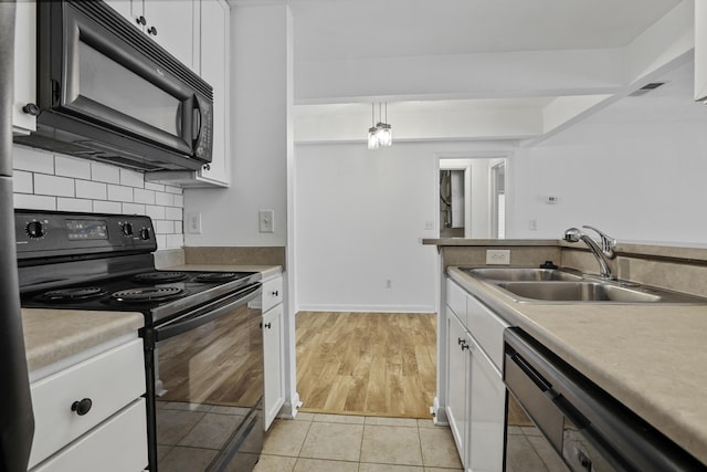 kitchen featuring light tile patterned flooring, pendant lighting, sink, white cabinets, and black appliances