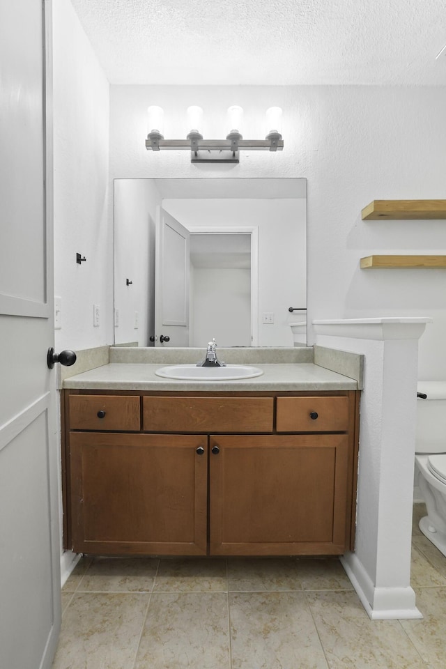 bathroom featuring tile patterned flooring, vanity, a textured ceiling, and toilet