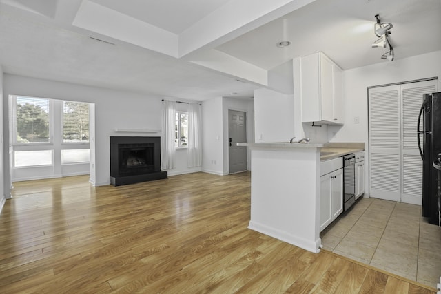 kitchen with sink, light hardwood / wood-style flooring, kitchen peninsula, white cabinets, and black appliances