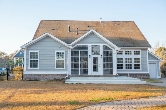 back of property featuring a shingled roof, a lawn, a sunroom, fence, and a garage