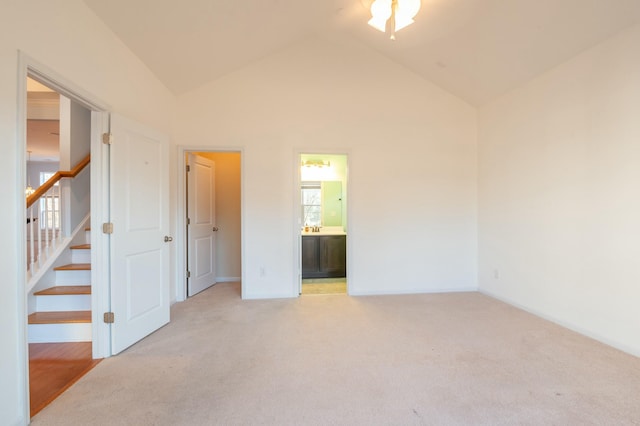 empty room featuring high vaulted ceiling, light colored carpet, and stairway