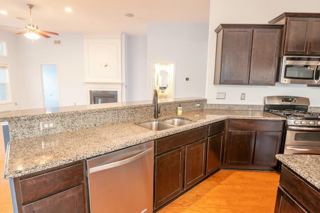 kitchen with visible vents, appliances with stainless steel finishes, dark brown cabinets, light wood-style floors, and a sink