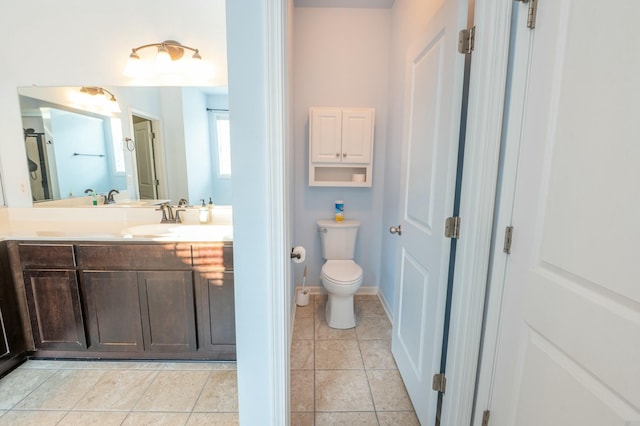 bathroom with toilet, vanity, baseboards, and tile patterned floors