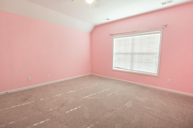 empty room featuring lofted ceiling, carpet flooring, visible vents, and baseboards