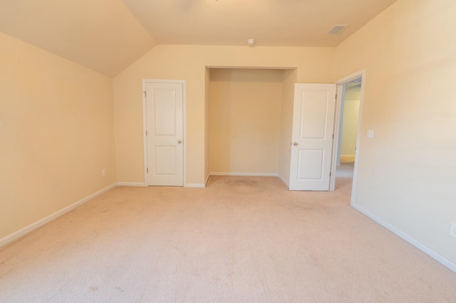 interior space featuring visible vents, baseboards, vaulted ceiling, and light colored carpet