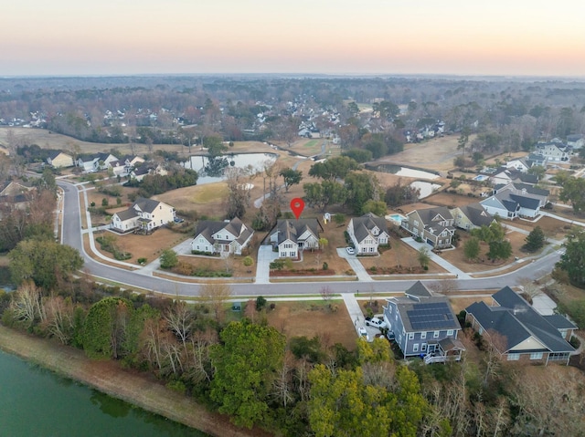 aerial view at dusk with a water view and a residential view