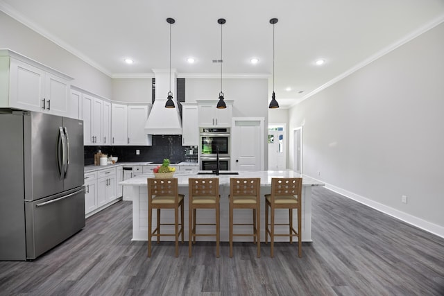 kitchen featuring appliances with stainless steel finishes, white cabinetry, dark hardwood / wood-style flooring, a kitchen bar, and a kitchen island with sink