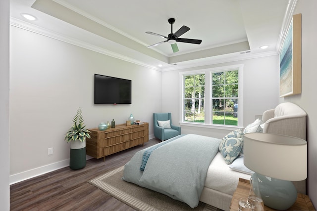 bedroom featuring ceiling fan, ornamental molding, a tray ceiling, and dark wood-type flooring