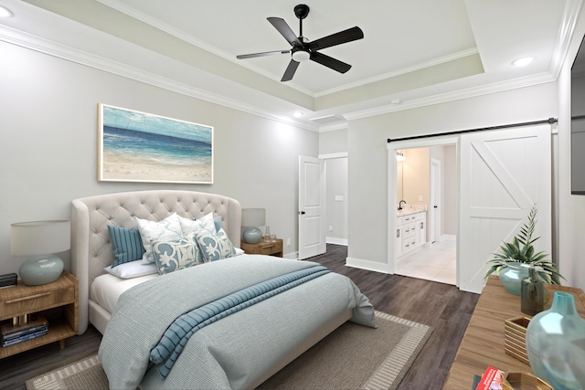 bedroom featuring a tray ceiling, ensuite bathroom, dark hardwood / wood-style flooring, ornamental molding, and ceiling fan