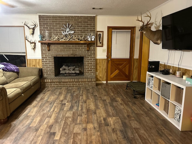 living room featuring dark wood-style flooring, wooden walls, a textured ceiling, a wainscoted wall, and visible vents