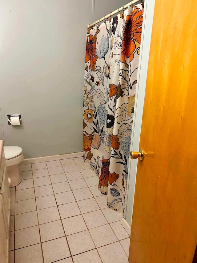 bathroom with toilet, tile patterned floors, baseboards, and curtained shower
