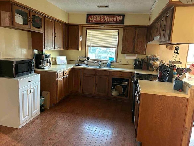 kitchen with visible vents, black appliances, hardwood / wood-style floors, light countertops, and a sink
