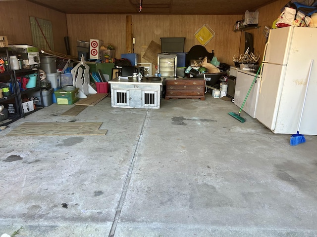 garage with wood walls and freestanding refrigerator