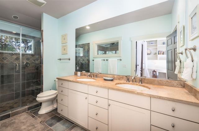 bathroom featuring vanity, a shower with shower door, and toilet