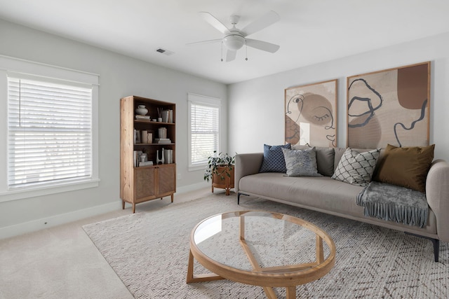 living area featuring carpet, visible vents, baseboards, and a ceiling fan