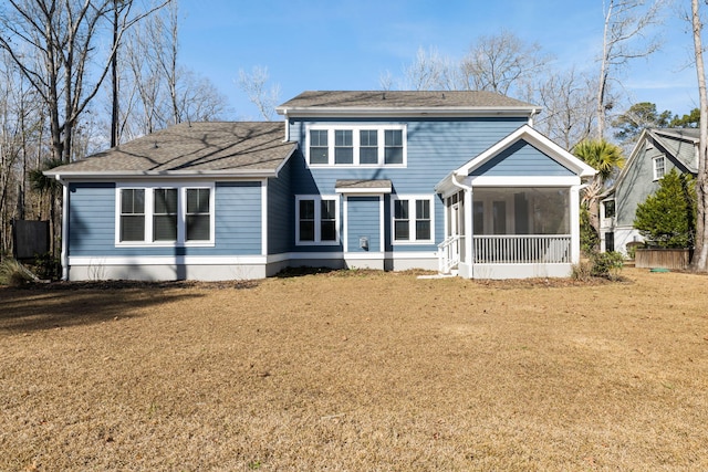 rear view of property featuring a sunroom, a shingled roof, and a yard