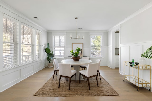 dining area featuring ornamental molding, plenty of natural light, an inviting chandelier, and a decorative wall