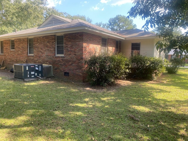 view of side of property with central AC unit and a yard