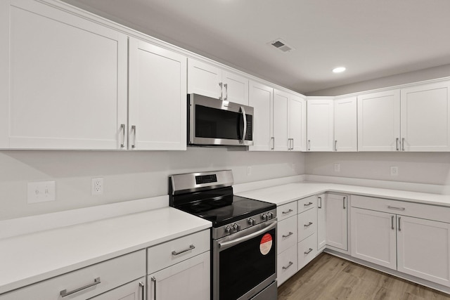 kitchen with appliances with stainless steel finishes, light wood finished floors, white cabinetry, recessed lighting, and visible vents