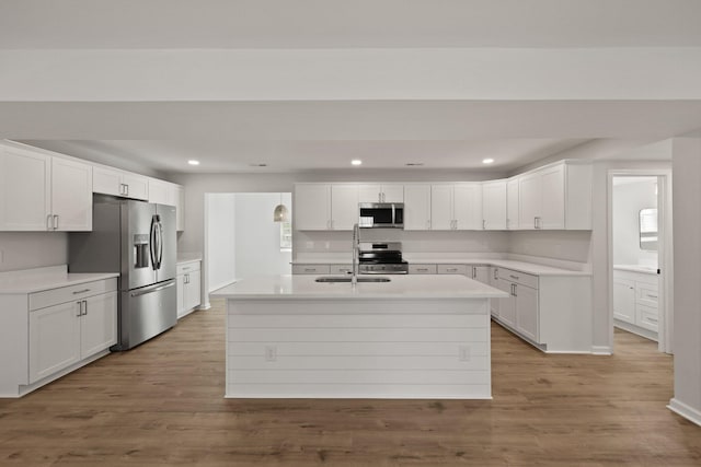 kitchen featuring appliances with stainless steel finishes, a sink, light countertops, white cabinetry, and recessed lighting