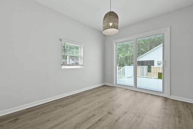 spare room with baseboards and wood finished floors