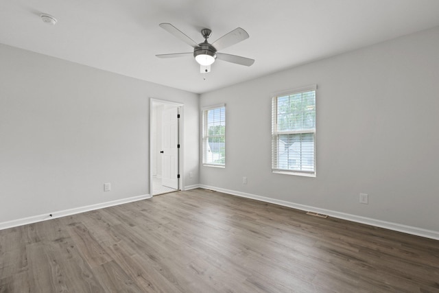 unfurnished room with a ceiling fan, baseboards, visible vents, and wood finished floors