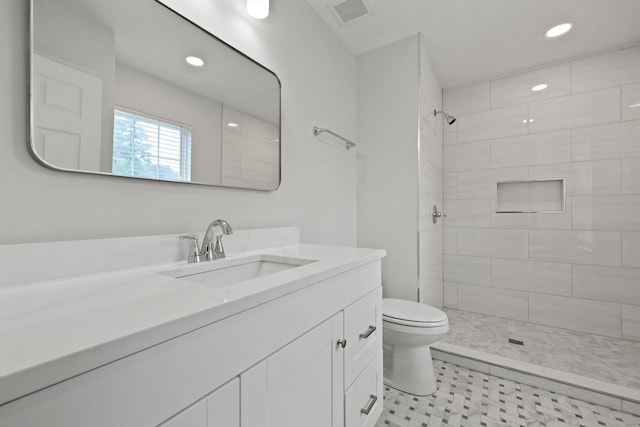 bathroom featuring visible vents, a tile shower, vanity, toilet, and recessed lighting