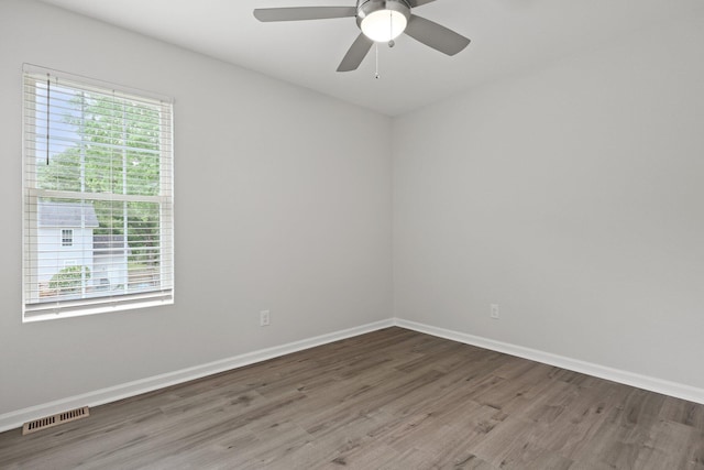 empty room featuring a ceiling fan, baseboards, visible vents, and wood finished floors