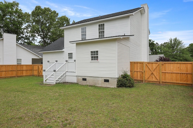back of property with a lawn, a fenced backyard, a gate, and crawl space