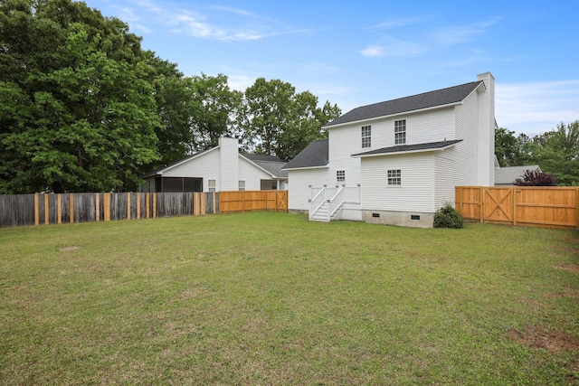 rear view of property featuring a yard, crawl space, a shingled roof, and a fenced backyard