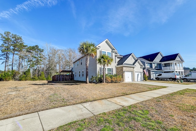 traditional-style home with a residential view, concrete driveway, an attached garage, and a front lawn