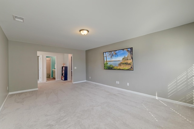 spare room with light colored carpet, visible vents, and baseboards