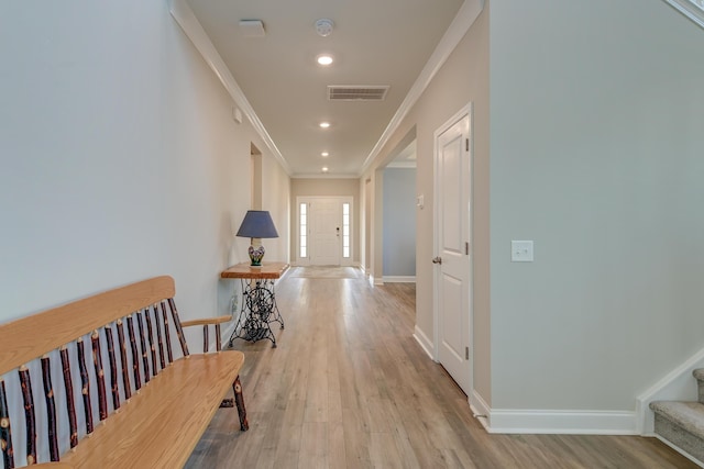 corridor with light wood-type flooring, stairs, visible vents, and crown molding