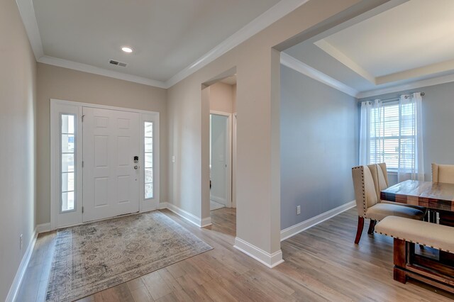 entryway with ornamental molding, light wood-type flooring, and baseboards