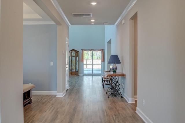 hall with recessed lighting, visible vents, baseboards, light wood-type flooring, and crown molding