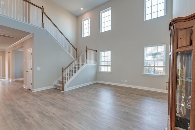 unfurnished living room with baseboards, stairway, a wealth of natural light, and light wood-style floors