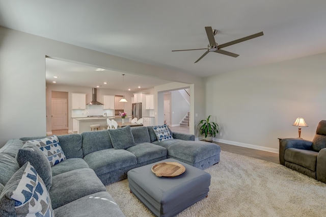 living room with light wood finished floors, baseboards, ceiling fan, stairs, and recessed lighting