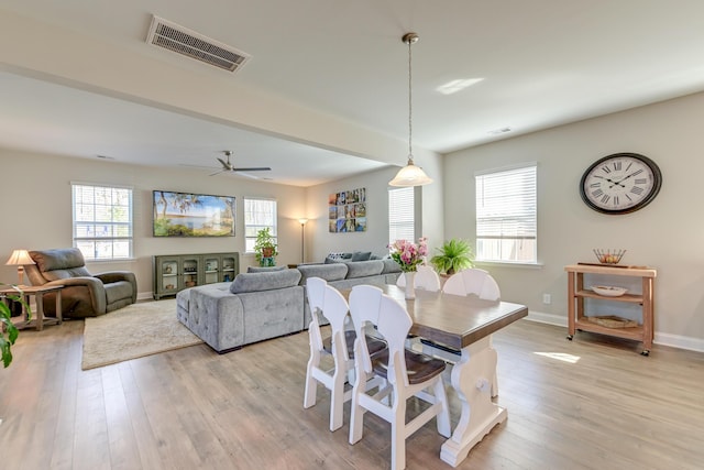 dining space with a ceiling fan, baseboards, visible vents, and light wood finished floors