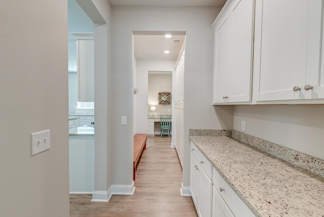 bar featuring light wood finished floors, baseboards, and visible vents