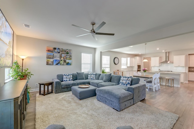 living room featuring recessed lighting, visible vents, light wood-style flooring, a ceiling fan, and baseboards